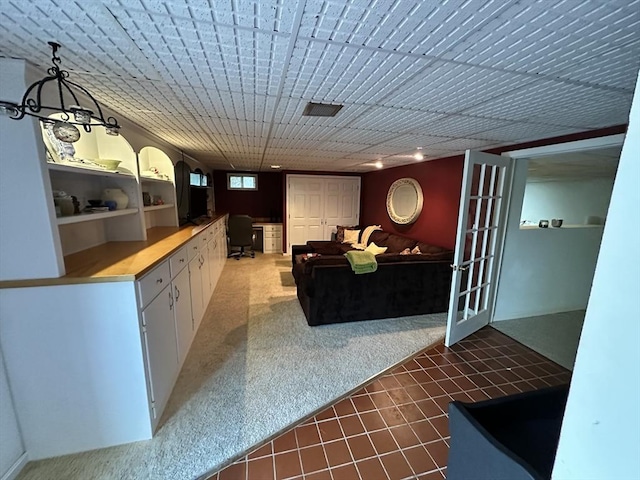 living area featuring visible vents, built in desk, and carpet