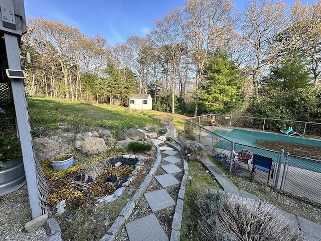 view of yard featuring fence, a storage unit, and an outdoor structure