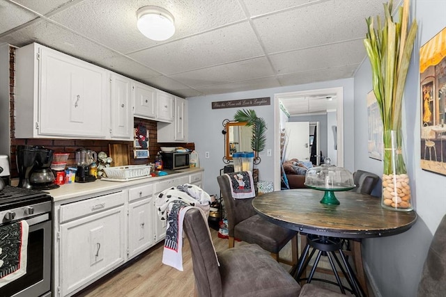 kitchen with light wood-type flooring, white cabinets, light countertops, and a drop ceiling