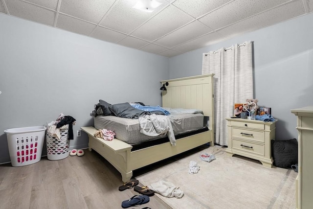 bedroom with light wood-style flooring and a paneled ceiling