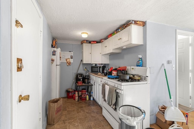 kitchen featuring white range with gas stovetop, stainless steel microwave, white cabinets, and a textured ceiling