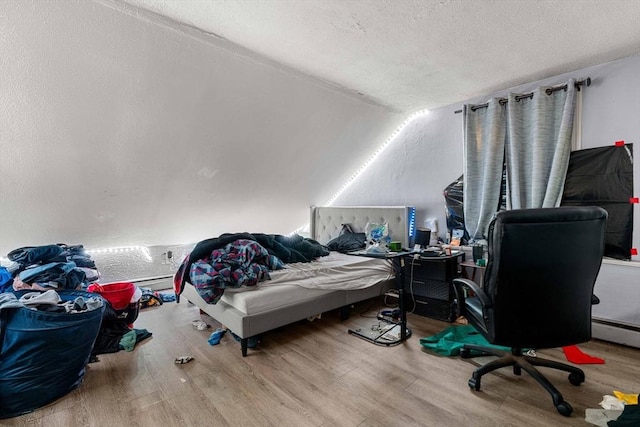 bedroom featuring vaulted ceiling, a textured ceiling, and light wood finished floors