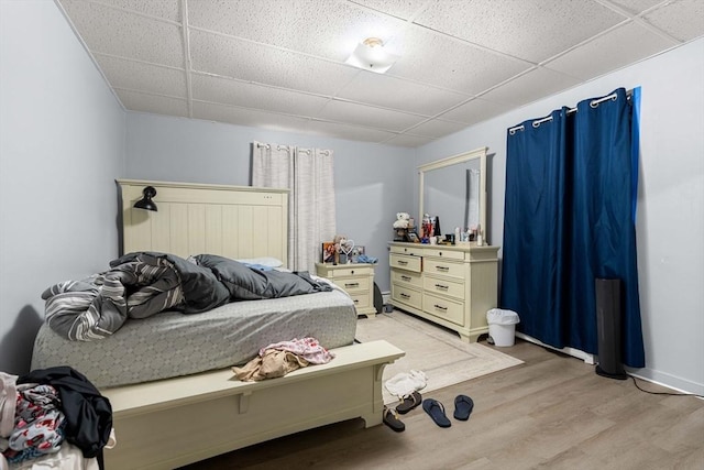 bedroom featuring a drop ceiling and light wood-style flooring