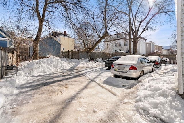 snowy yard featuring a residential view and fence