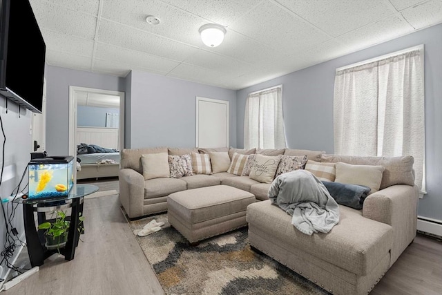 living room featuring baseboard heating, wood finished floors, and a paneled ceiling