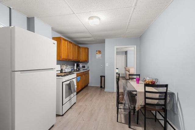 kitchen featuring brown cabinets, white appliances, light countertops, and light wood finished floors