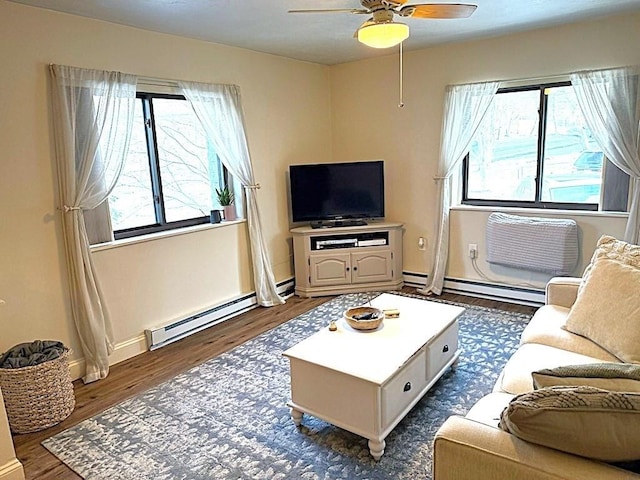 living room with a baseboard heating unit, a wealth of natural light, and dark wood-type flooring