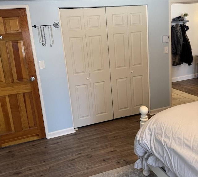 bedroom with dark wood-style floors, a closet, and baseboards