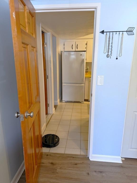 corridor featuring light wood-style floors and baseboards