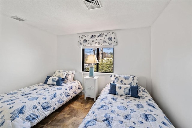 bedroom with a textured ceiling, visible vents, and tile patterned flooring
