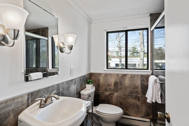 bathroom with a sink, toilet, a wainscoted wall, tile walls, and a shower stall