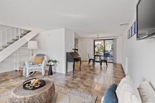 living area featuring stairs, a chandelier, visible vents, and tile patterned flooring