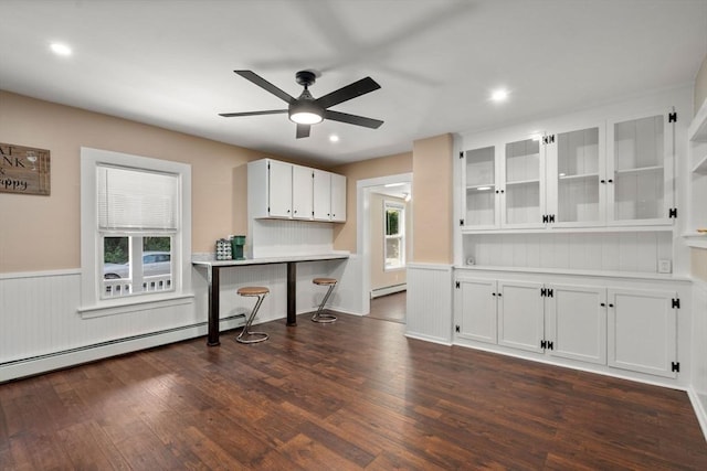448 Washington St, Warren, MA 01083 - kitchen featuring dark wood-style floors, wainscoting, a baseboard heating unit, a ceiling fan, and white cabinets