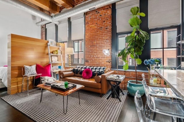 living room with visible vents, wood-type flooring, a high ceiling, and brick wall