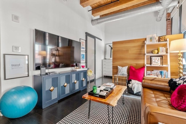 living area with beam ceiling, a high ceiling, and wood finished floors