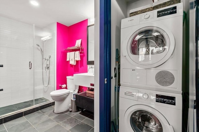 clothes washing area featuring tile patterned flooring and stacked washer and dryer