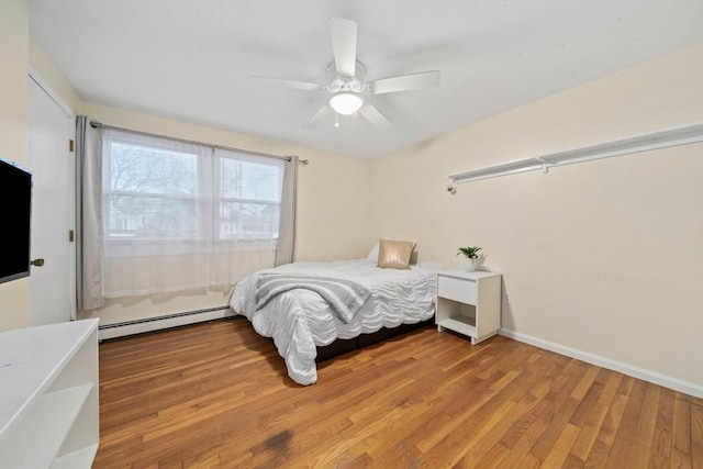 bedroom with hardwood / wood-style flooring, ceiling fan, and a baseboard heating unit