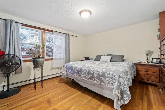 bedroom with a baseboard radiator and hardwood / wood-style floors