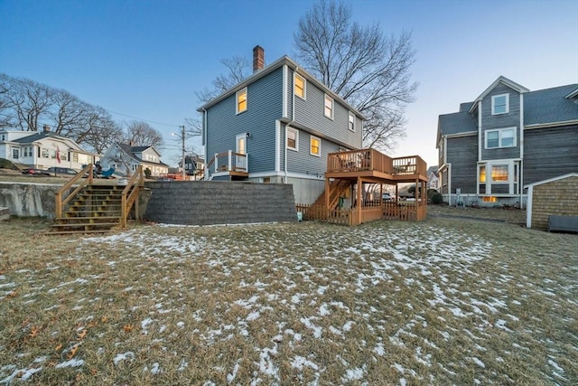 snow covered back of property with a deck