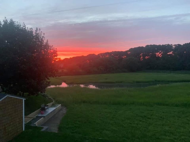 yard at dusk featuring a water view