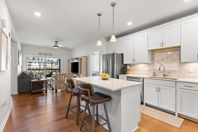 230 Martins Lndg Unit 310, North Reading, MA 01864 - kitchen featuring appliances with stainless steel finishes, decorative backsplash, a kitchen breakfast bar, wood finished floors, and a kitchen island