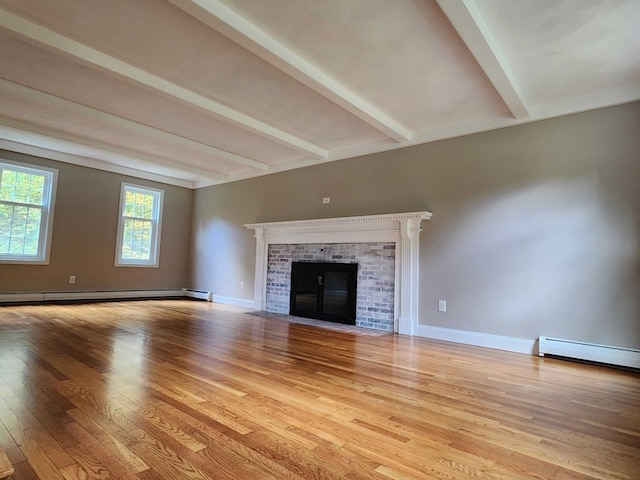 unfurnished living room featuring a fireplace, baseboard heating, beam ceiling, and light hardwood / wood-style floors