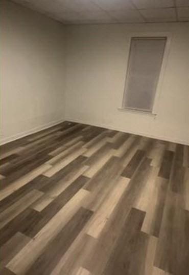 empty room with a drop ceiling and dark wood-type flooring