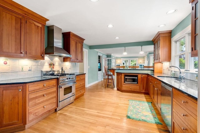 9 Palmer Rd, Marblehead, MA 01945 - kitchen with wall chimney exhaust hood, stainless steel appliances, a sink, a peninsula, and light wood-type flooring