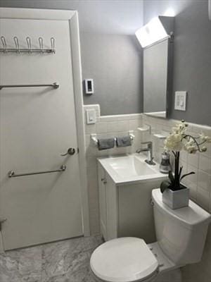 bathroom featuring tile walls, vanity, and toilet