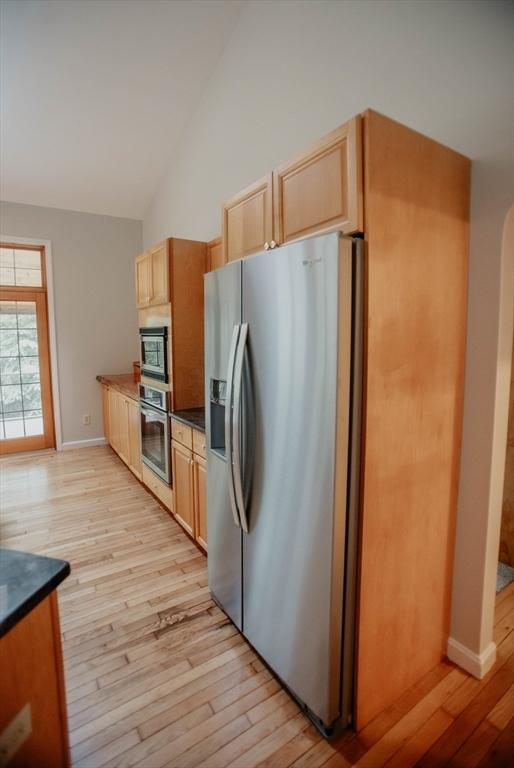 251 Butterworth Rd, Barre, MA 01005 - kitchen featuring stainless steel appliances, light wood finished floors, dark countertops, light brown cabinetry, and high vaulted ceiling