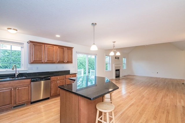 kitchen featuring dishwasher, a sink, a breakfast bar, light wood-style flooring, and open floor plan