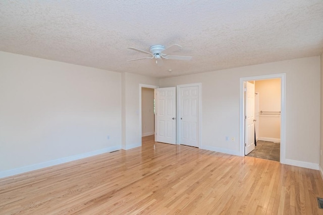 unfurnished bedroom featuring light wood finished floors, baseboards, a textured ceiling, a closet, and ceiling fan