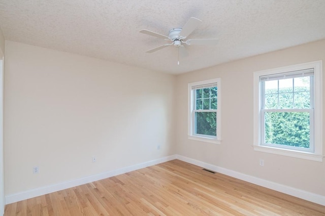 empty room featuring light wood-style floors, baseboards, a textured ceiling, and a ceiling fan