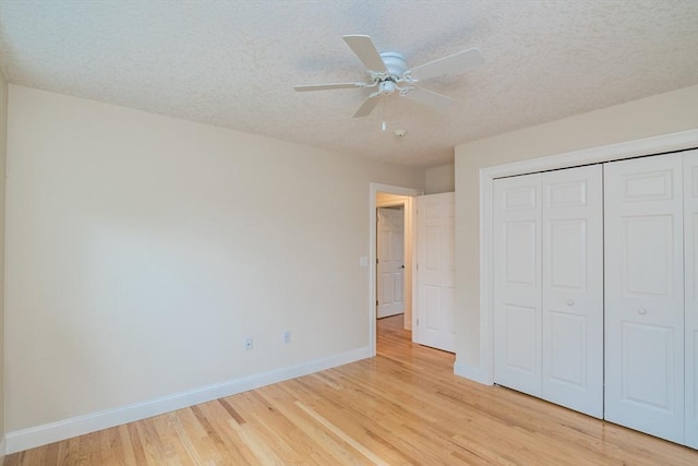unfurnished bedroom featuring light wood-style flooring, baseboards, a textured ceiling, and a closet