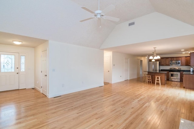unfurnished living room with light wood-type flooring, high vaulted ceiling, a chandelier, a ceiling fan, and baseboards