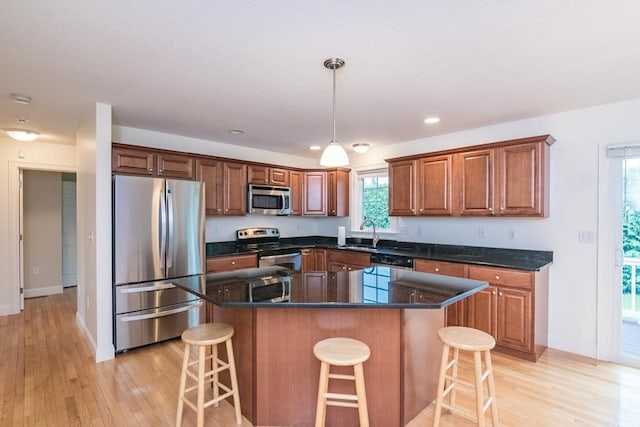 kitchen with appliances with stainless steel finishes, a sink, light wood-style floors, a kitchen bar, and recessed lighting