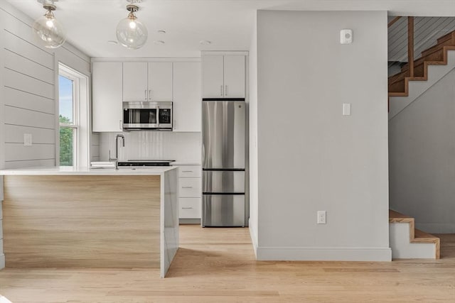 88 Maverick St Unit 3, Boston, MA 02128 - kitchen with appliances with stainless steel finishes, light wood-style floors, white cabinets, tasteful backsplash, and light countertops