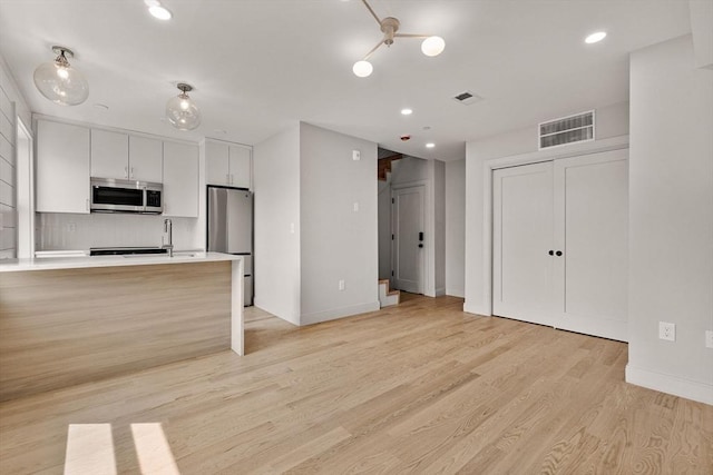 88 Maverick St Unit 3, Boston, MA 02128 - kitchen with stainless steel appliances, light countertops, light wood-type flooring, white cabinets, and recessed lighting
