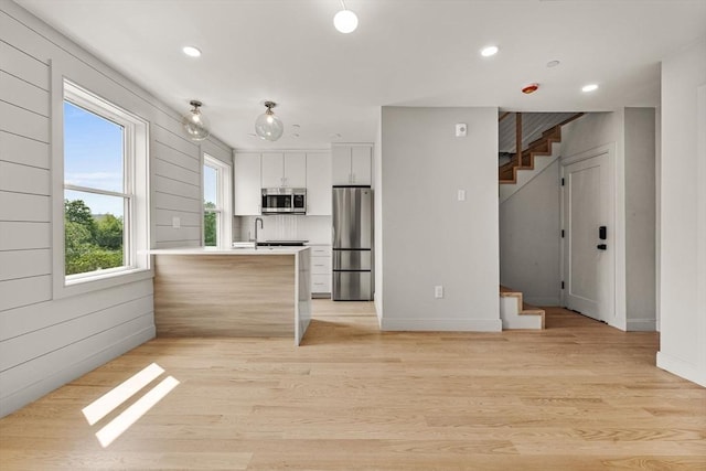 88 Maverick St Unit 3, Boston, MA 02128 - kitchen featuring stainless steel appliances, a peninsula, light countertops, white cabinetry, and light wood-style flooring