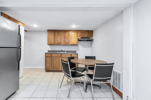 16 Pacific St, Lynn, MA 01902 - kitchen featuring freestanding refrigerator, under cabinet range hood, brown cabinetry, dark countertops, and light tile patterned floors