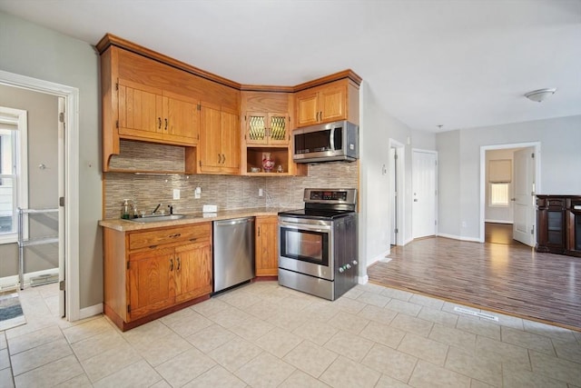 kitchen featuring decorative backsplash, sink, light tile patterned floors, and stainless steel appliances