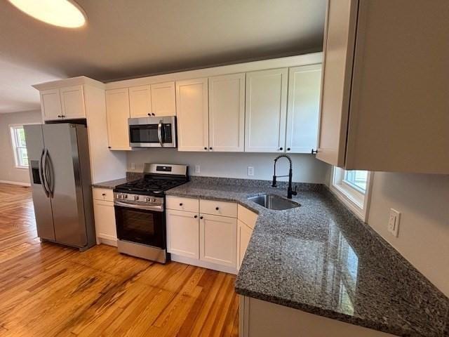 404 Brayton Ave, Fall River, MA 02721 - kitchen featuring stainless steel appliances, white cabinets, light wood finished floors, and dark stone counters