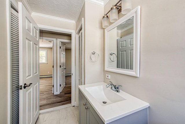 bathroom with marble finish floor, crown molding, a baseboard heating unit, vanity, and a textured ceiling