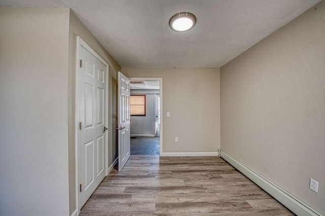 unfurnished room featuring light wood finished floors, baseboards, and baseboard heating