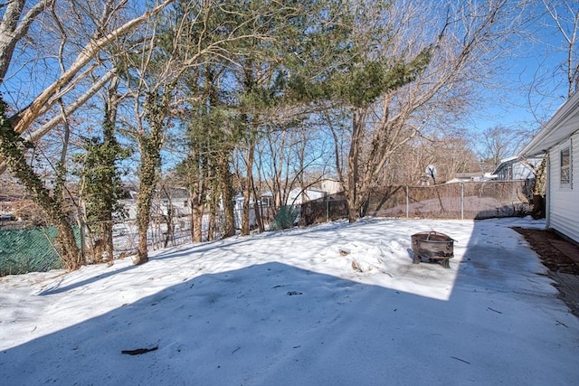 yard layered in snow featuring an outdoor fire pit and a fenced backyard