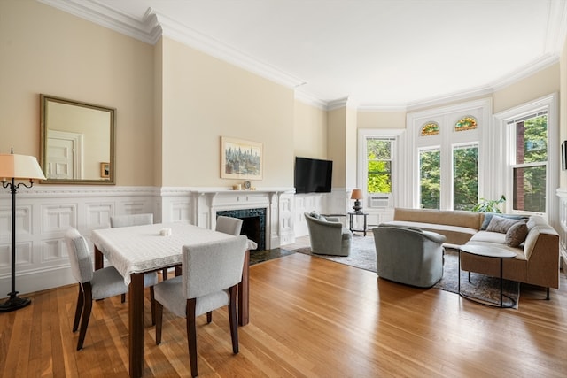 dining area featuring a fireplace, crown molding, and light hardwood / wood-style floors