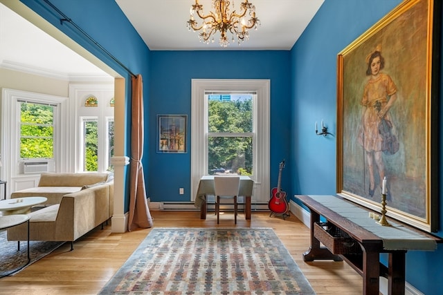 living area with light wood-type flooring, cooling unit, a baseboard radiator, ornamental molding, and a chandelier