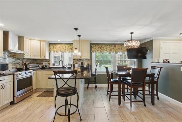 544 Main St, Stoneham, MA 02180 - kitchen with wall chimney exhaust hood, stainless steel range, cream cabinets, dark countertops, and a sink