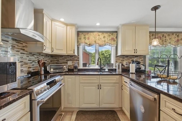 544 Main St, Stoneham, MA 02180 - kitchen with wall chimney exhaust hood, a sink, appliances with stainless steel finishes, cream cabinetry, and backsplash