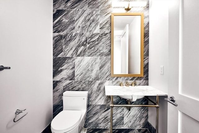 bathroom featuring sink, toilet, and tile walls